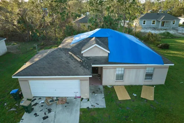 Managing roof emergencies in storms made easy for Oklahoma homeowners 9 A storm-damaged Oklahoma roof being temporarily covered showing managing roof emergencies in storms.